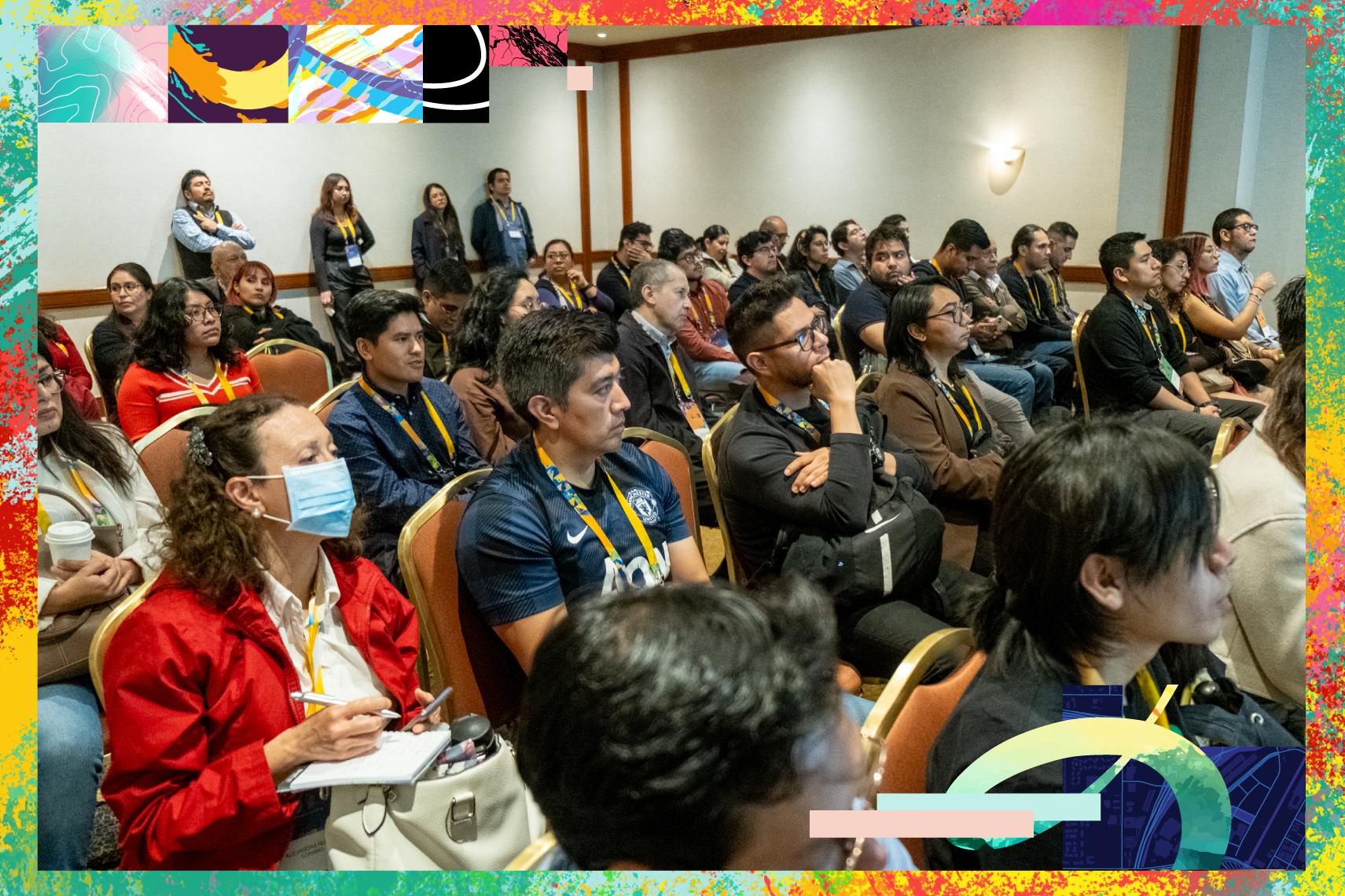 Person in a gray blazer and glasses laughing with head thrown back while clutching a laptop to their chest