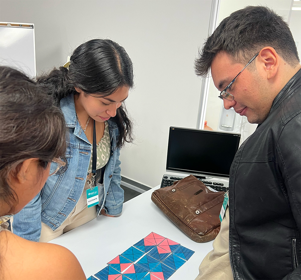 Persona con pelo largo y sudadera de color blanco roto sonriente sobre un mapa con regiones en tonos azul, turquesa, naranja y amarillo