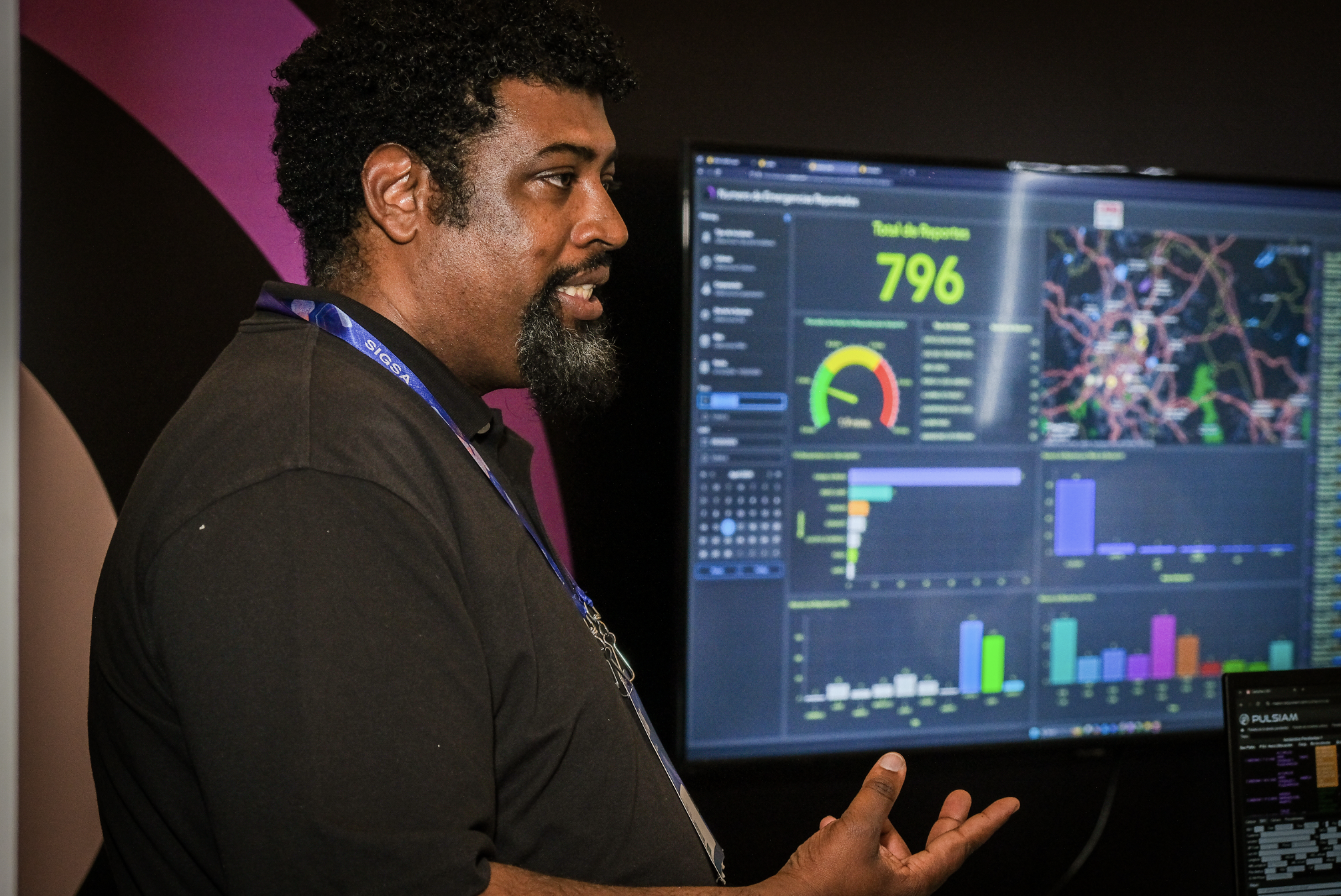 Three trade show attendees looking at a wall-mounted monitor where a map is displayed
