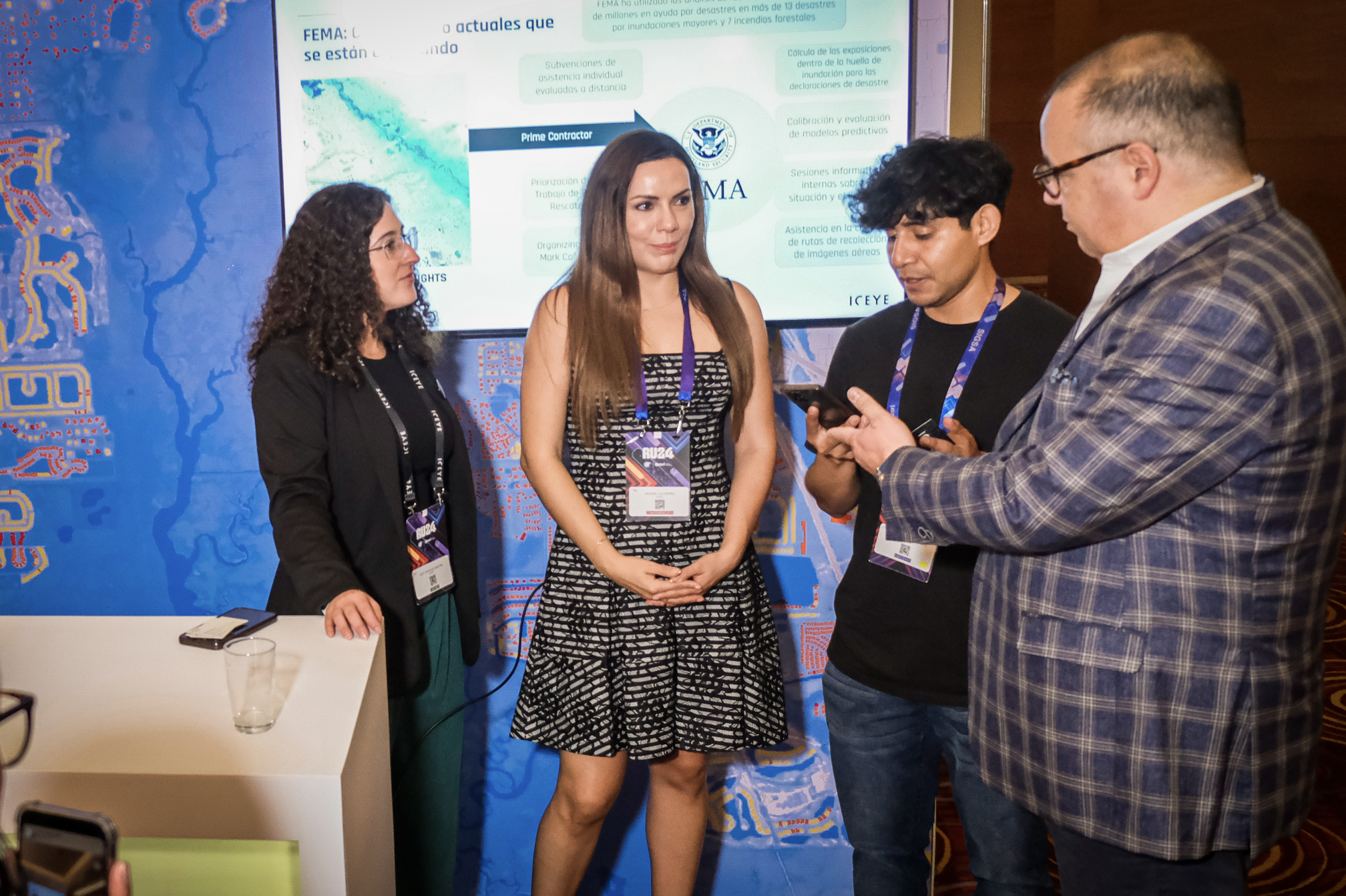 Three people standing togetjer at a trade show, looking at a tablet one of them is holding