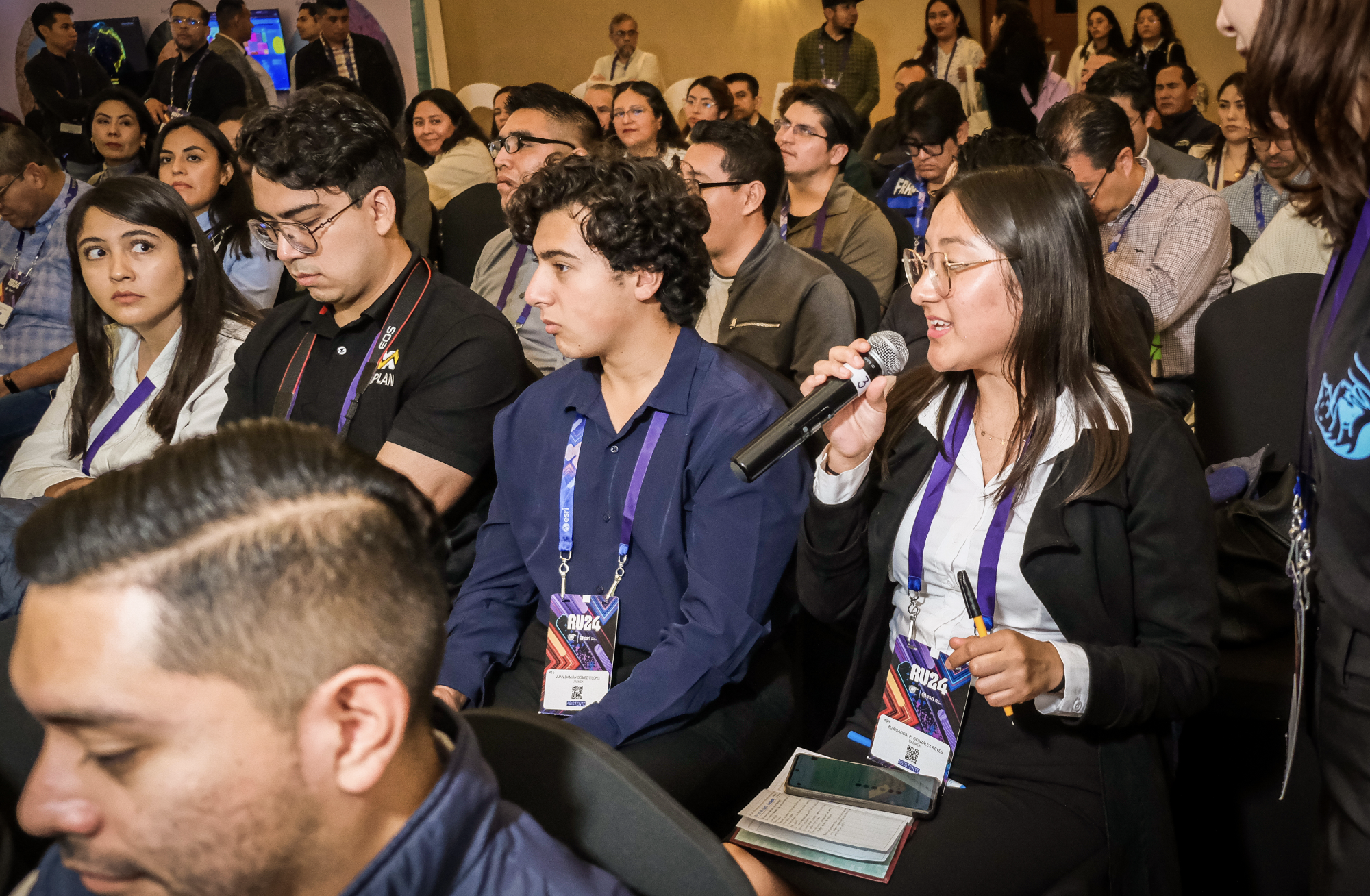 A presenter onstage, seen from behind the audience