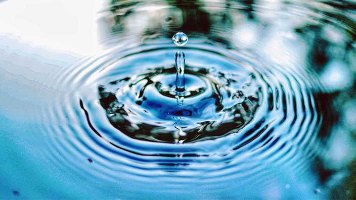 Una gota de agua generando ondas en un charco más grande