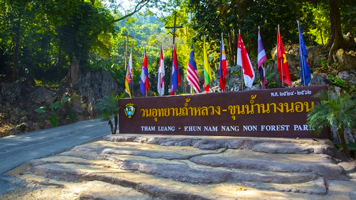 Cartel a la entrada de la cueva de Tham Luang con las banderas de los países que colaboraron en el rescate. 