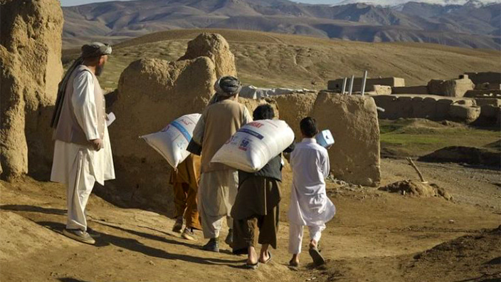 Los habitantes de los pueblos recogen raciones de alimentos en Afganistán
