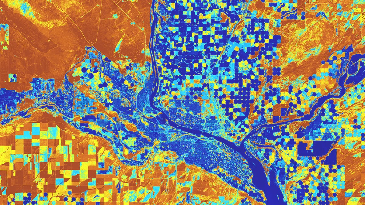 Una imagen satelital muestra terrenos a lo largo de un río con campos cuadrados y circulares resaltados en azul, naranja y amarillo.