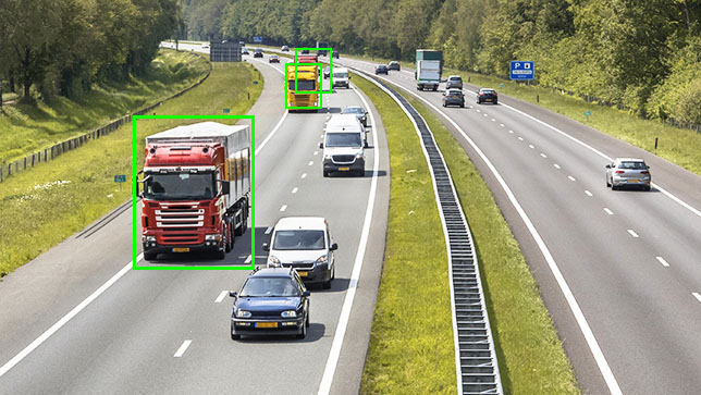 Vehículos en una autopista de cuatro carriles con un gran camión articulado rojo dentro de un rectángulo verde