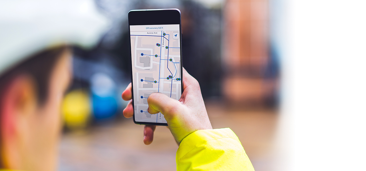 Trabajador de servicios capturando datos de interiores en un teléfono para cartografiar las condiciones y ubicaciones de los activos.
