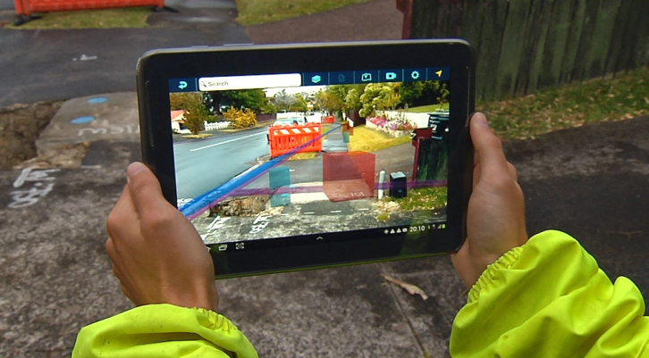 Manos que sujetan un iPad en un exterior que muestra una obra para visualizar el contexto espacial 