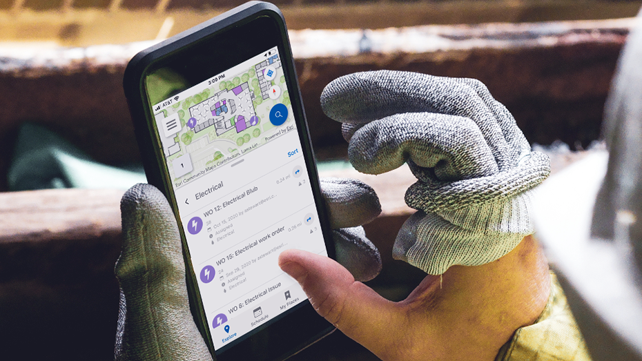Trabajador de mantenimiento sujetando un teléfono móvil que muestra un mapa de interiores