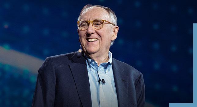 Una foto de Jack Dangermond usando un auricular y sonriendo en el escenario de una conferencia