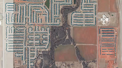 Una imagen aérea de una gran urbanización llena de casas de tejados azules enclavadas en zonas de tierra de color marrón rojizo.