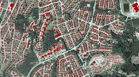 Área urbanizada con estructuras resaltadas en rojo rodeada de zonas verdes 