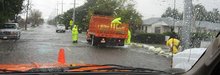 County flood control crews sandbag a location to prevent further flooding of private property